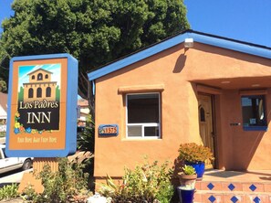 A small, single-story building with a blue roof and orange walls, labeled as 'Los Padres INN' with a signboard featuring a building illustration. - Los Padres Inn (San Luis Obispo)