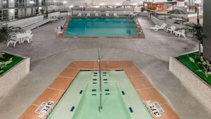 Una piscina interior con tabla de clavados, sillas de descanso y zona de la piscina con barandilla.