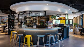 A modern bar area with stools, a counter, and a coffee machine.
