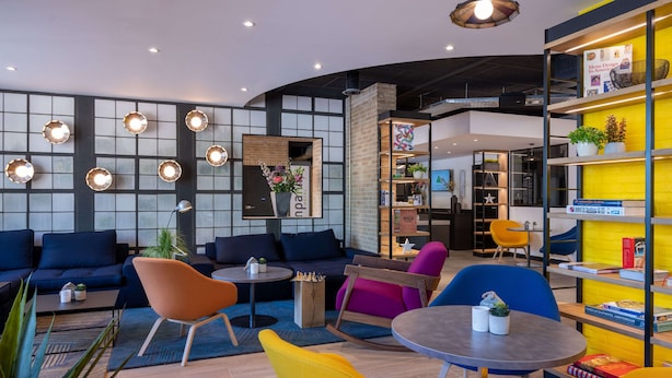 Ein stilvoller Lounge-Bereich mit Sofas, Sesseln und einem Couchtisch. Bücherregale mit Büchern und Dekorationselementen.