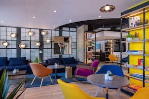 Ein stilvoller Lounge-Bereich mit Sofas, Sesseln und einem Couchtisch. Bücherregale mit Büchern und Dekorationselementen.