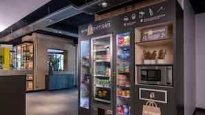 Ein Mini-Boutique-Automaten mit einer Auswahl an Snacks und Getränken, einer Mikrowelle und einem Zahlungsbereich.