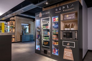 Ein Mini-Boutique-Automaten mit einer Auswahl an Snacks und Getränken, einer Mikrowelle und einem Zahlungsbereich.