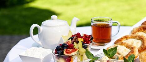 A picnic setup with a teapot, cups, and various food items on a table.