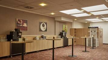 Un hall d’hôtel comprenant un comptoir d’accueil, un présentoir de confiseries et un espace dédié au café.