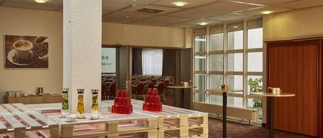 A hotel lobby with a reception desk, a large window with a view, and a display of glassware and red plastic cups.