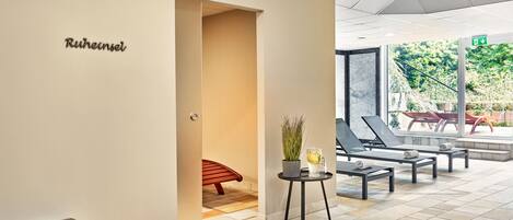 Un vestíbulo moderno con un mostrador de recepción, una zona de estar con sillones y vistas al exterior.