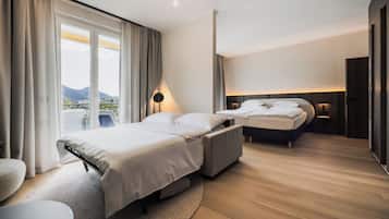 A modern hotel room with a large bed, a smaller bed, a seating area, and a view of the outdoors.