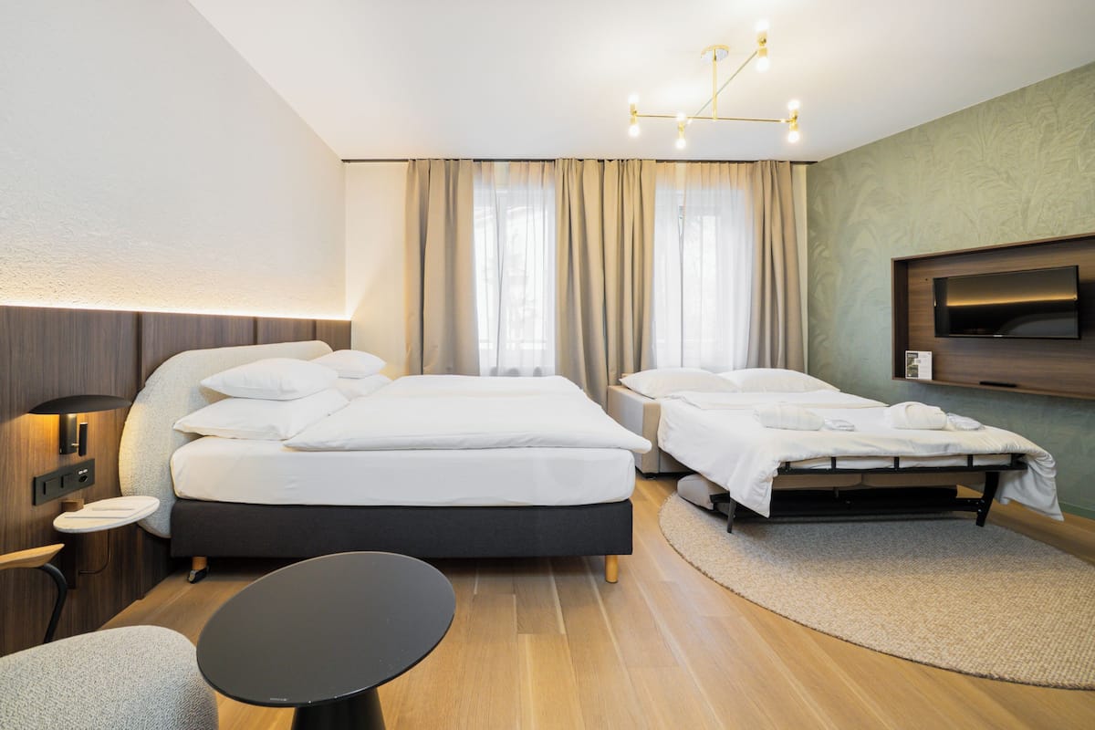 A hotel room with two beds, a TV, a desk, and a chair.