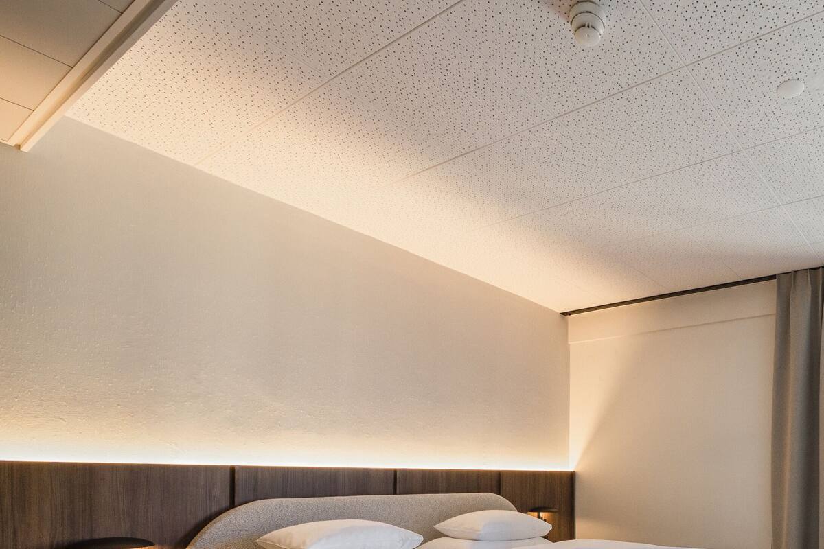 A modern bedroom with a bed, bedside table, and a wall-mounted light fixture.