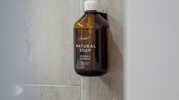 Eine Flasche Natürliche Seife an einer Wand befestigt.