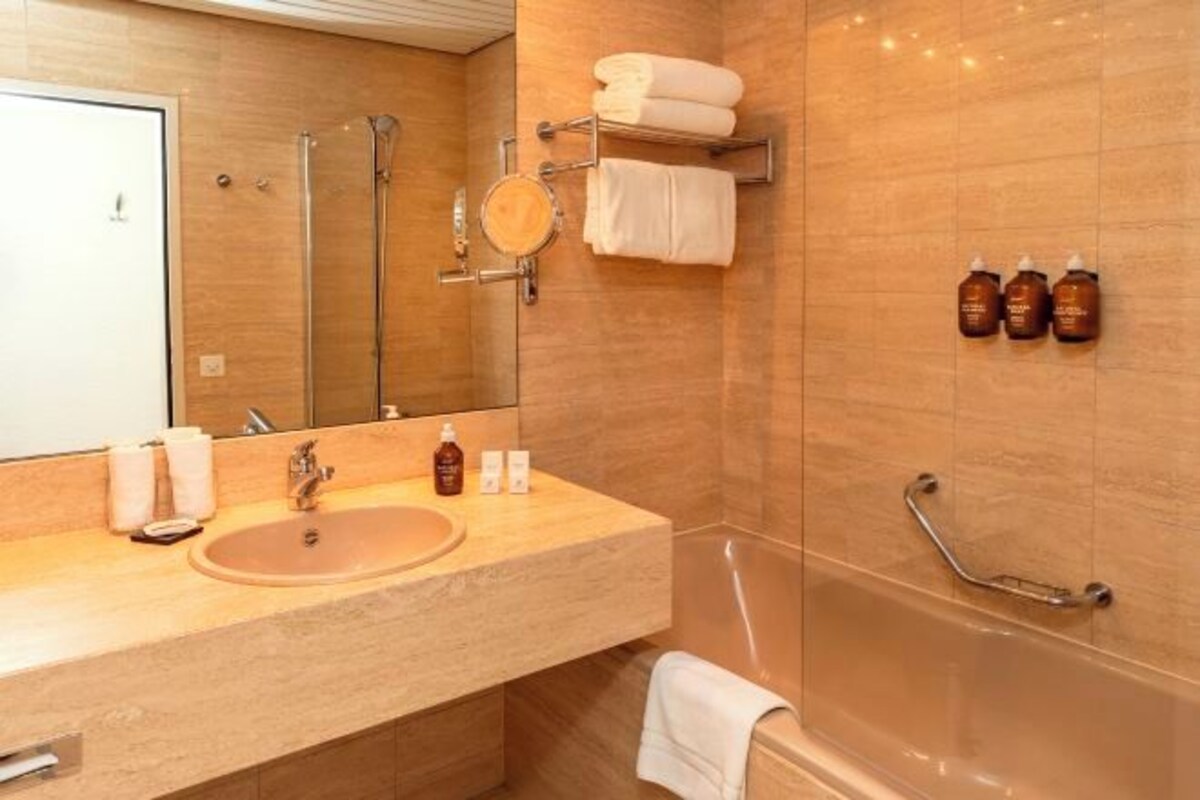 A modern bathroom with a sink, mirror, towel rack, and shower.