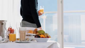 Une table dressée pour le petit-déjeuner, avec des aliments typiques et une vue sur les montagnes.