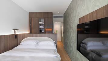Una habitación de hotel moderna con una cama grande, armario empotrado y un espejo.