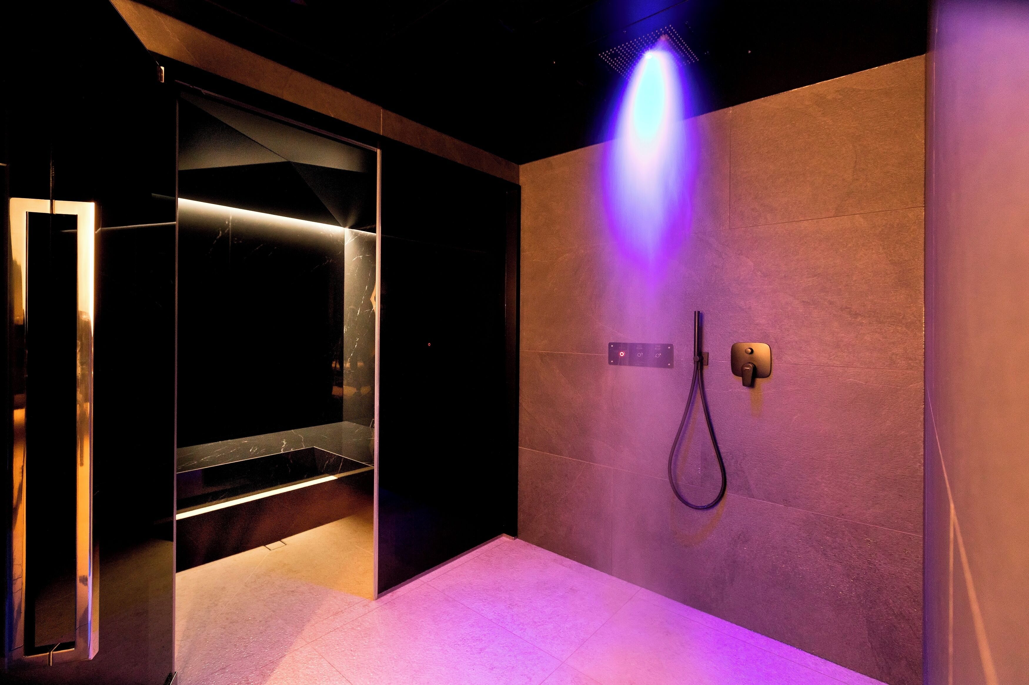 A modern bathroom with a glass enclosure, a heated floor, and a wall-mounted shower.