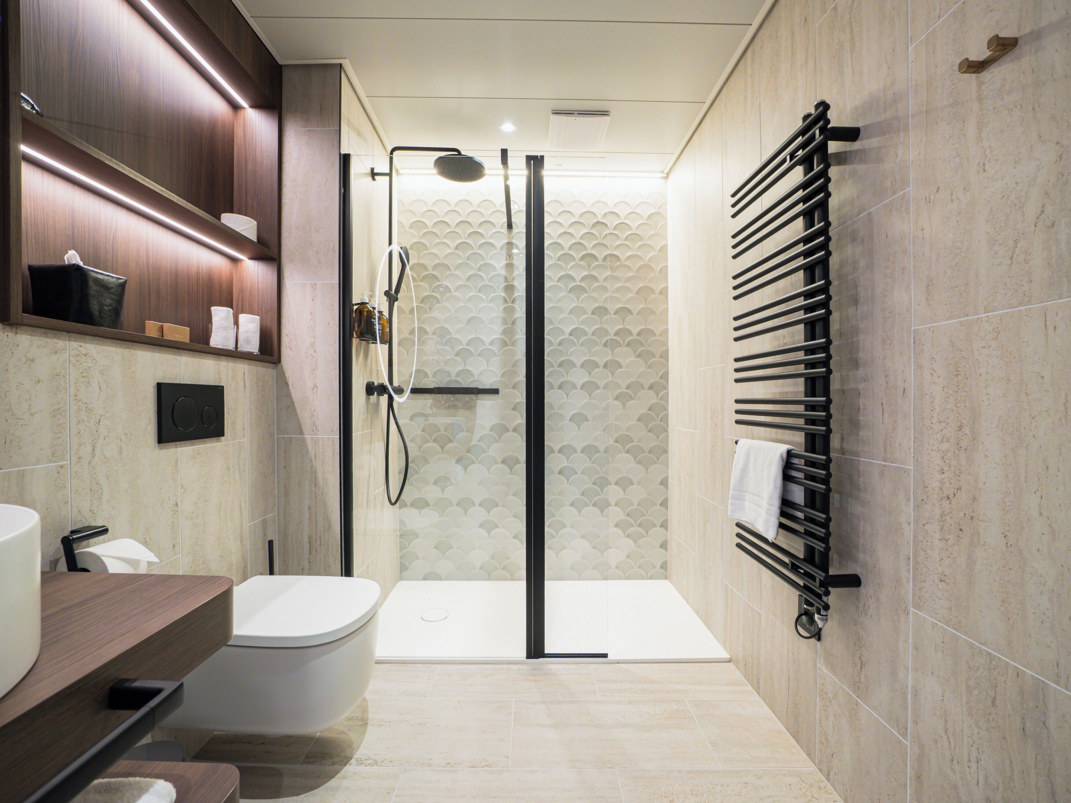 A modern bathroom with a toilet, sink, shower, and towel rack.