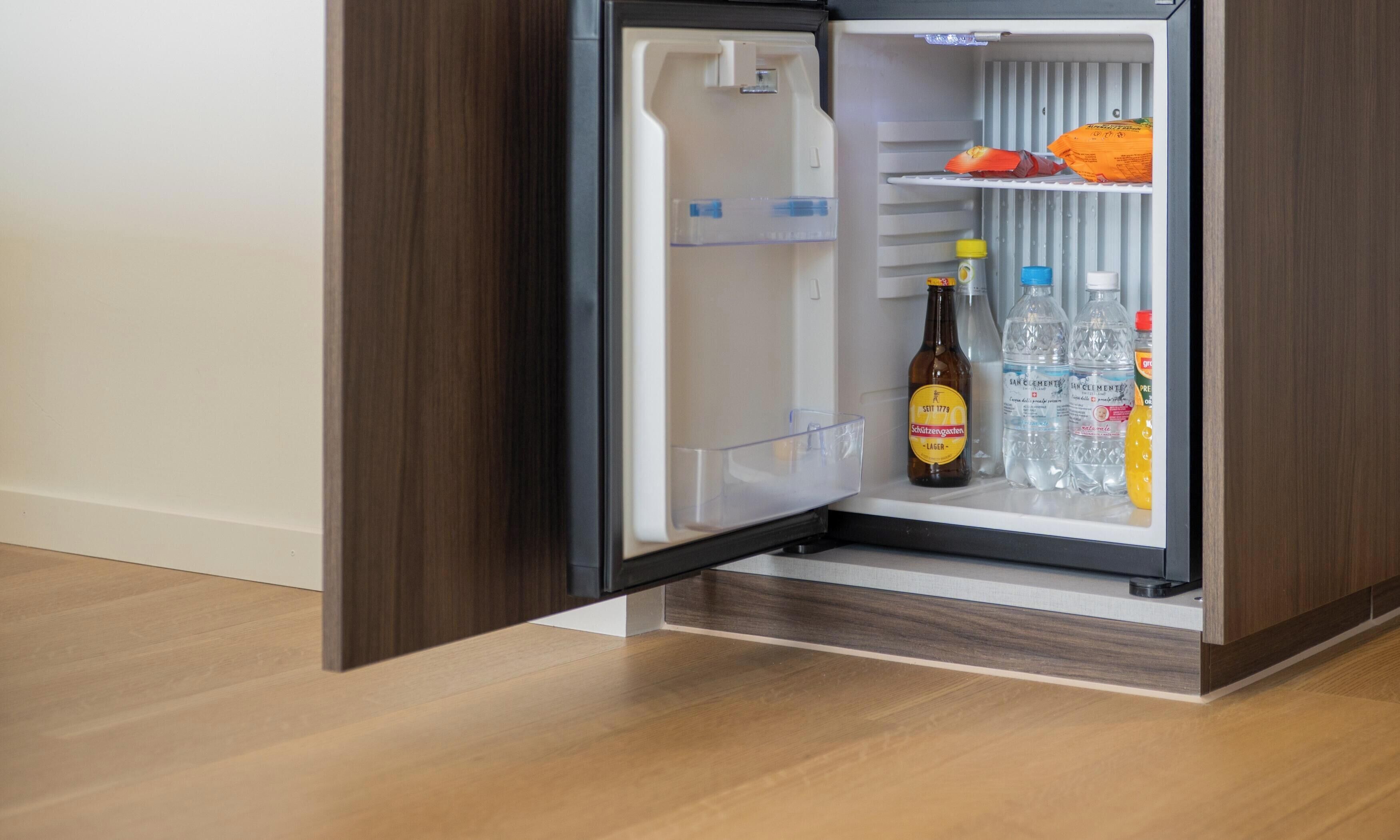 A refrigerator with a bottle of beer and bottled water.