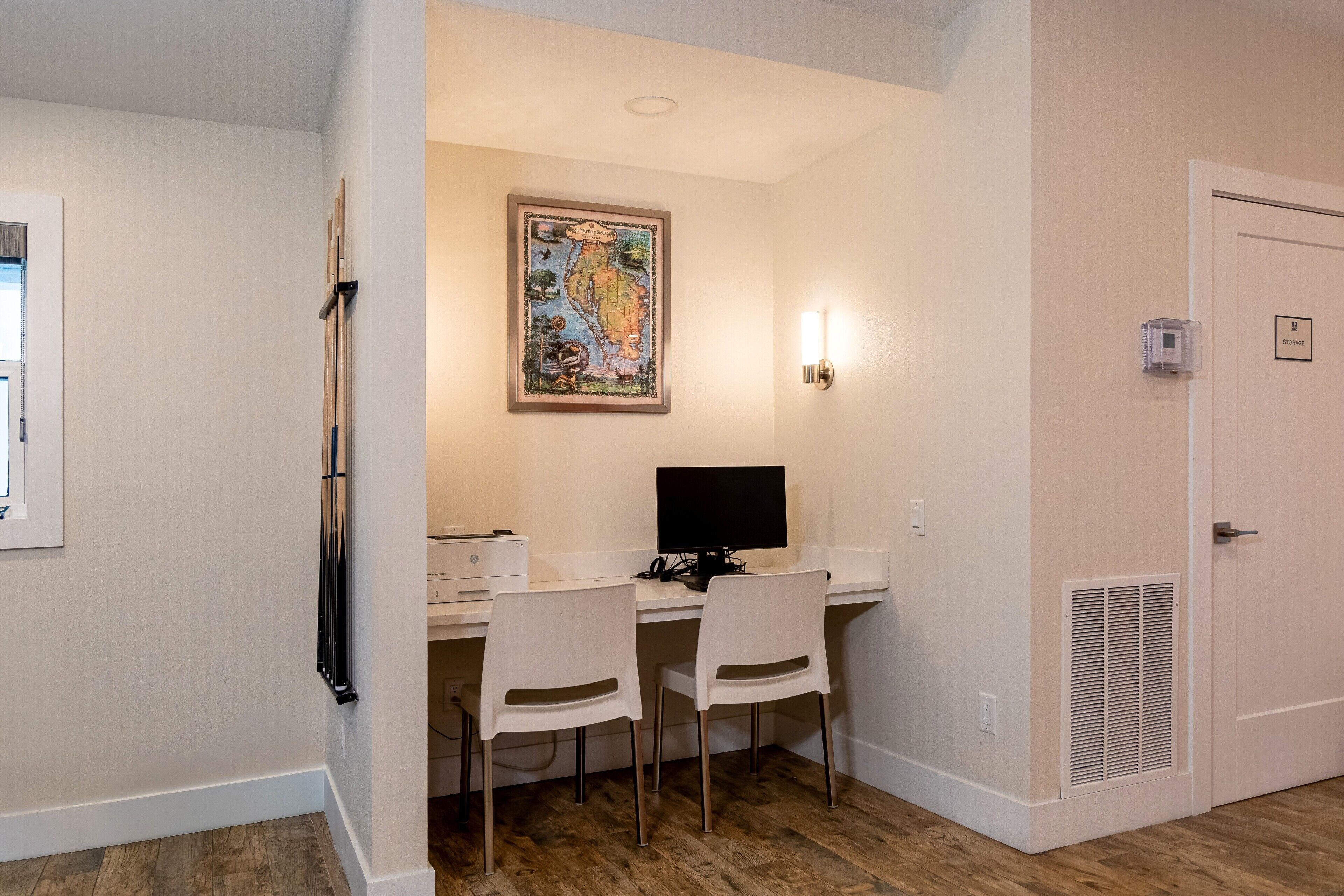 A room with a desk, two chairs, a computer, a framed map, and a storage sign.