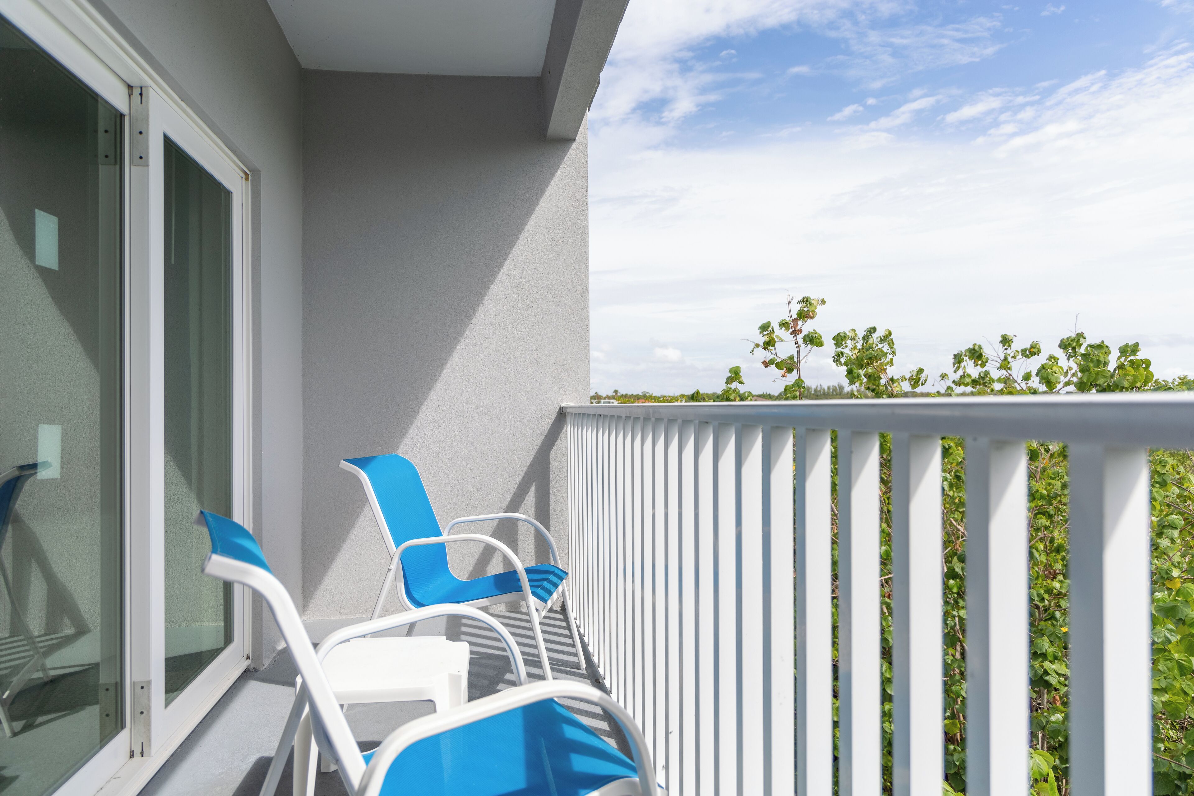 A balcony with white railings and a glass door.