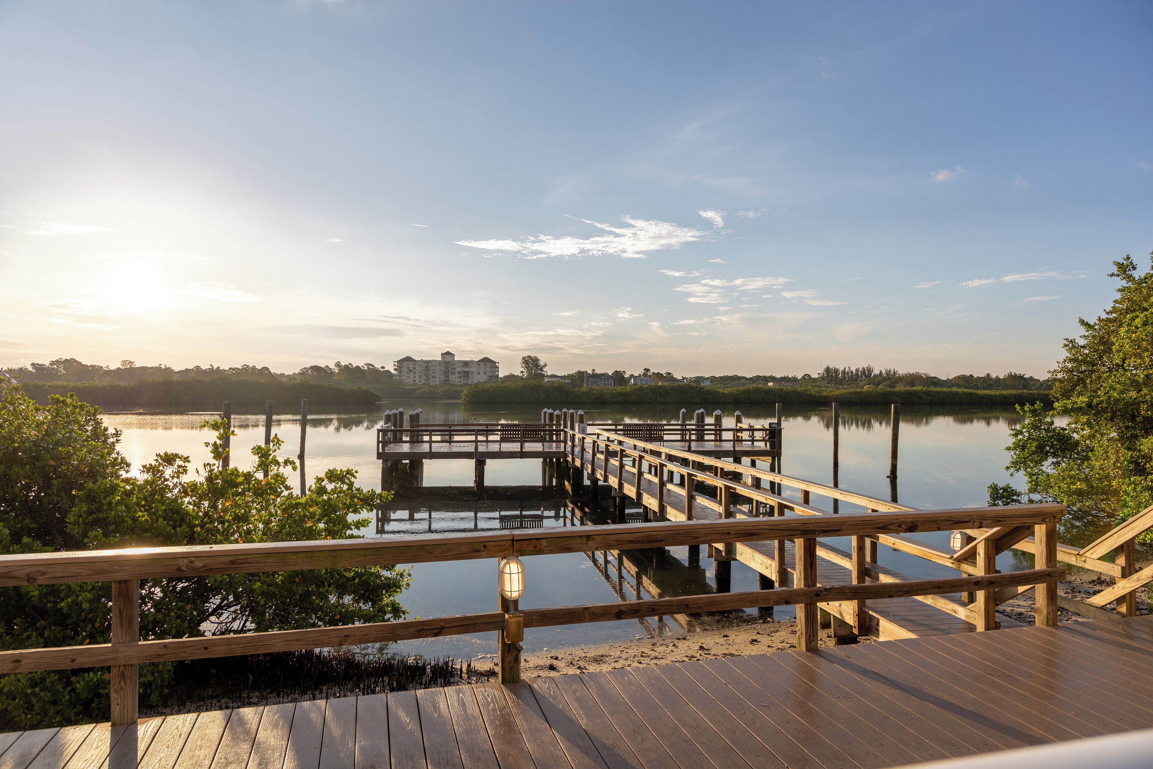 A wooden pier extending into calm water with a clear sky.