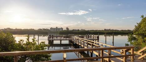 A wooden pier extending into calm water with a clear sky.