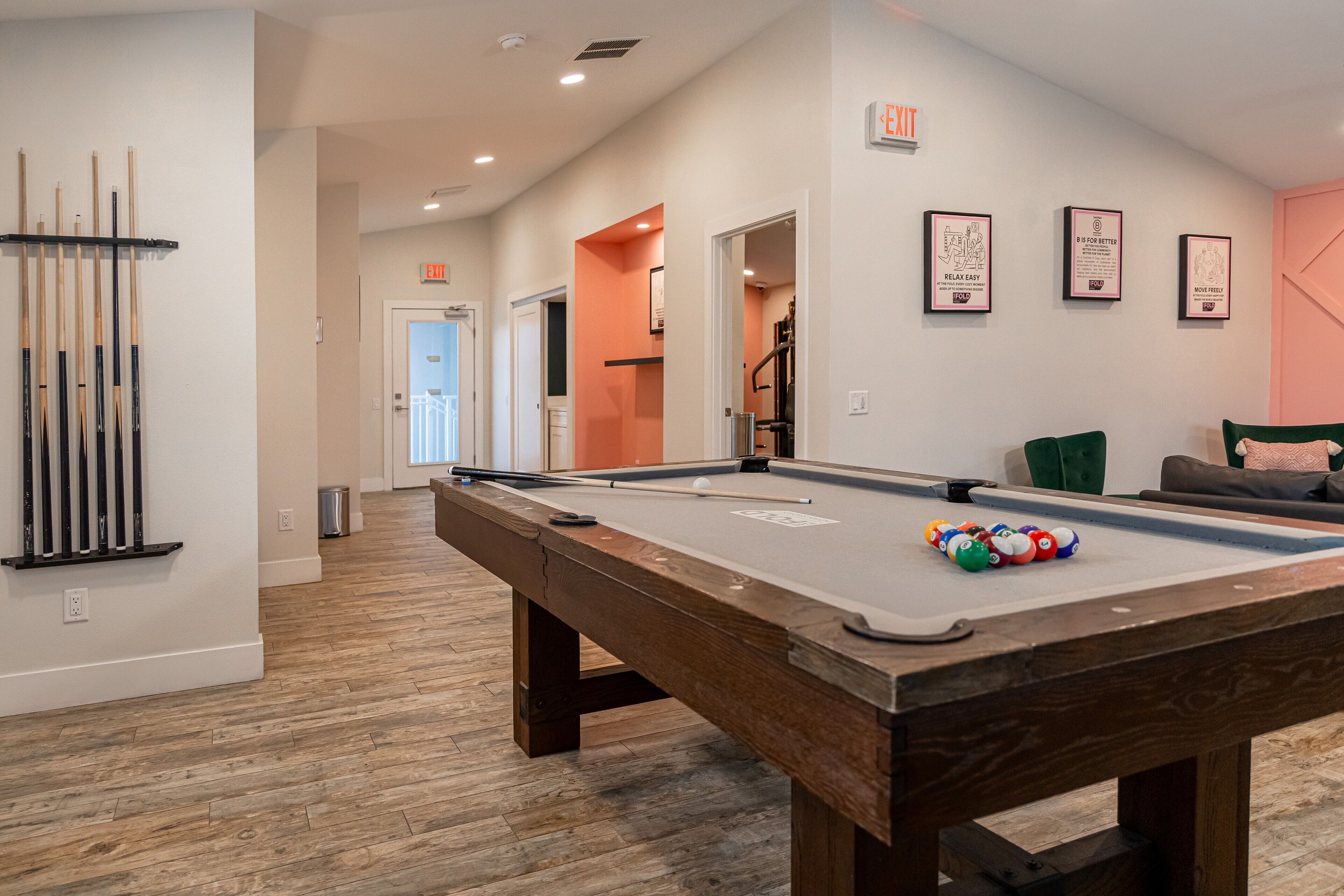 A pool table with balls, a cue rack, and a billiards cue stick.