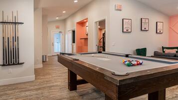 A pool table with balls, a cue rack, and a billiards cue stick.