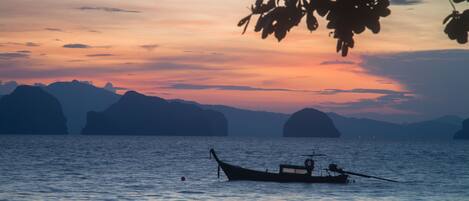 A boat on calm water with distant mountains and a sunset.