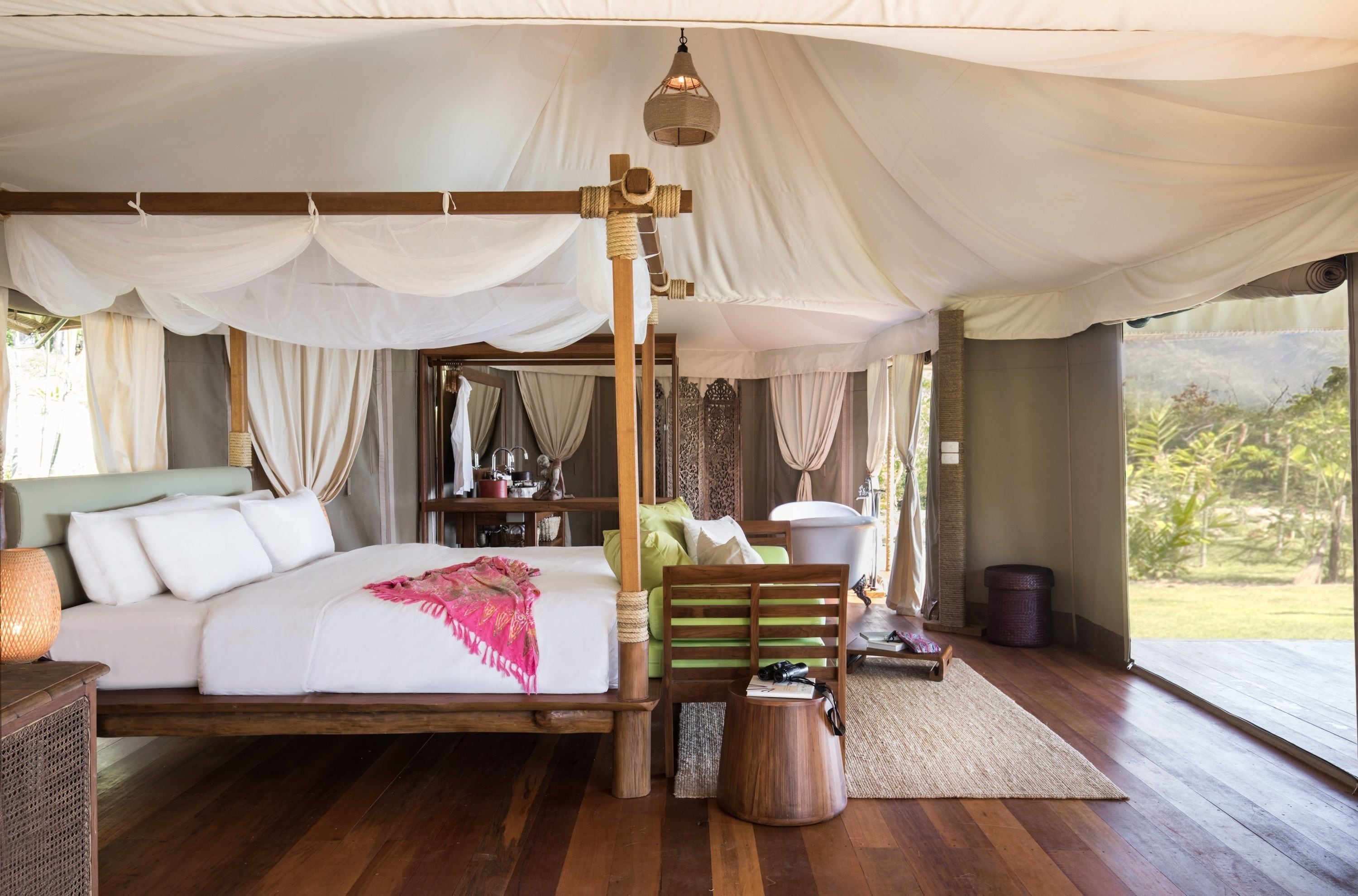 A spacious bedroom with a large bed, wooden headboard, and a view of the outdoors.