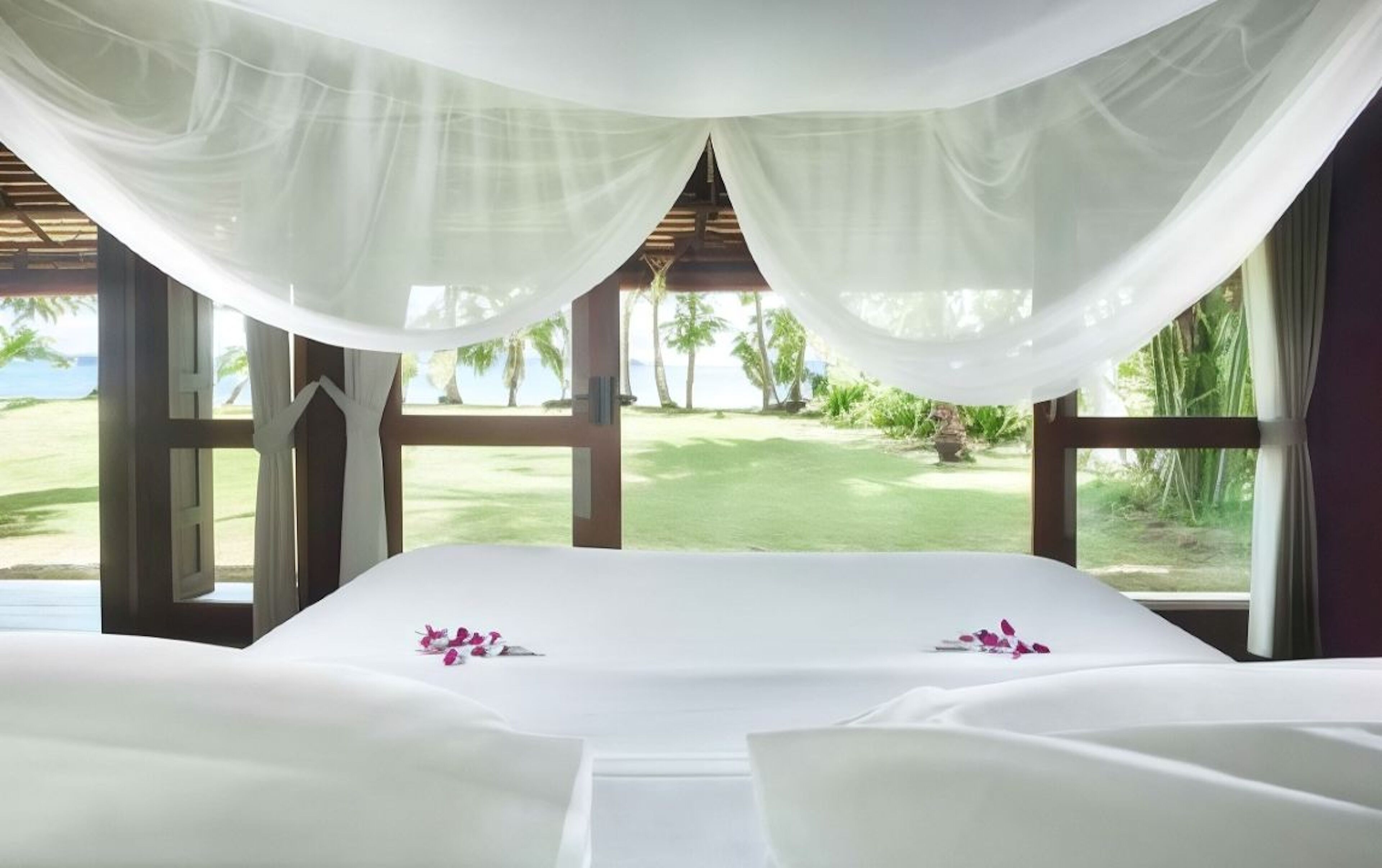 A room with a bed, large windows, and a view of a golf course.