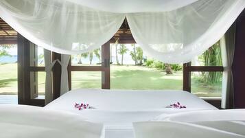 A room with a bed, large windows, and a view of a golf course.