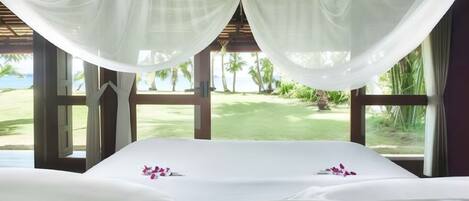 A room with a bed, large windows, and a view of a golf course.