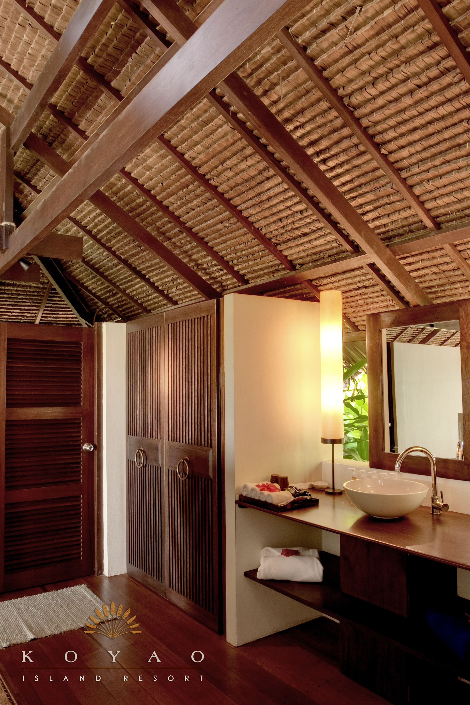 A wooden ceiling with woven patterns, a wooden door, a white sink with a bowl, and a mirror.