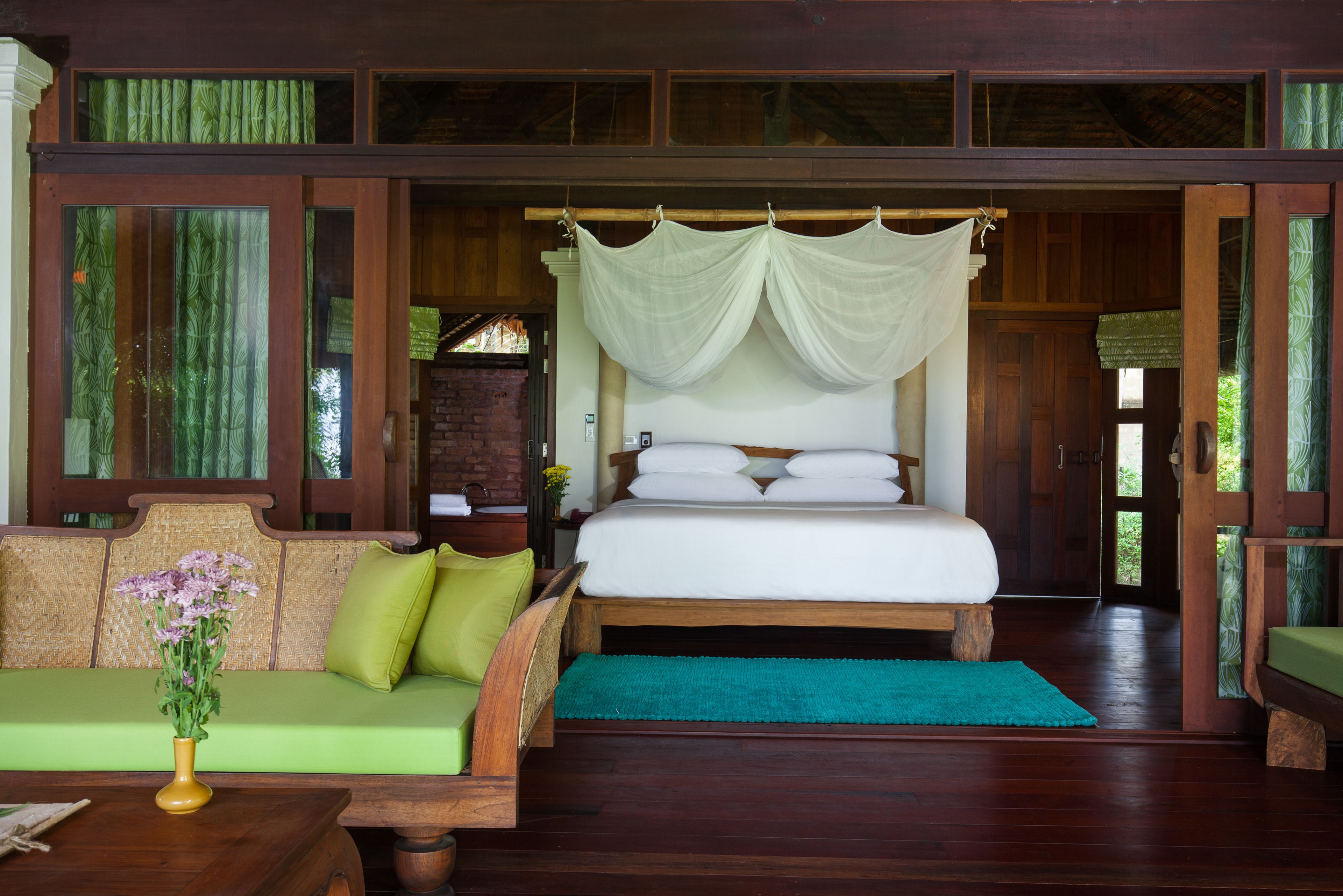 A bedroom with a bed, a sofa, and a wooden floor.