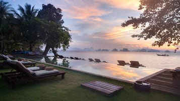 Relax by the pool overlooking a calm body of water.