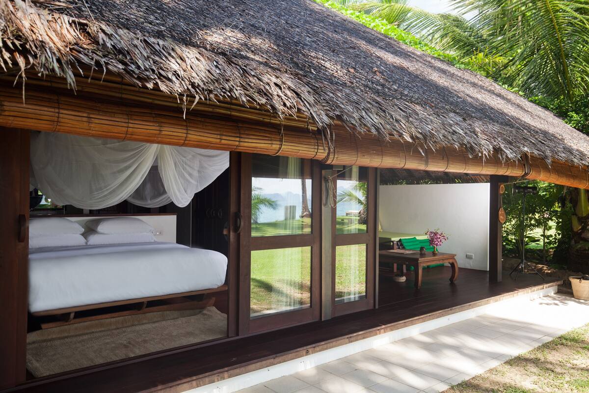 A room with a bed, a small table, and a window with a view of the outdoors.