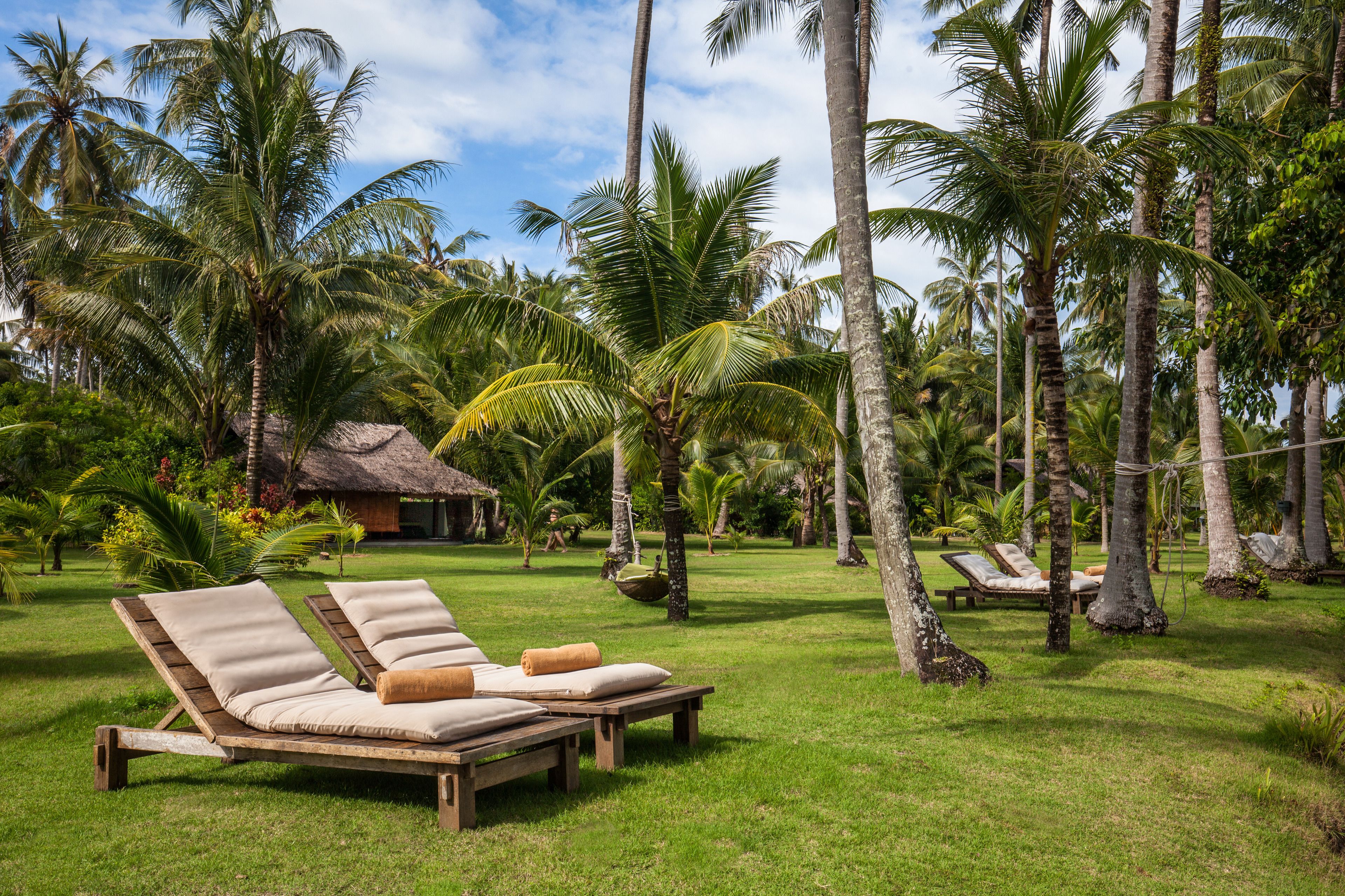 Un resort tropical con sillones de madera y una cabaña de techo de paja.