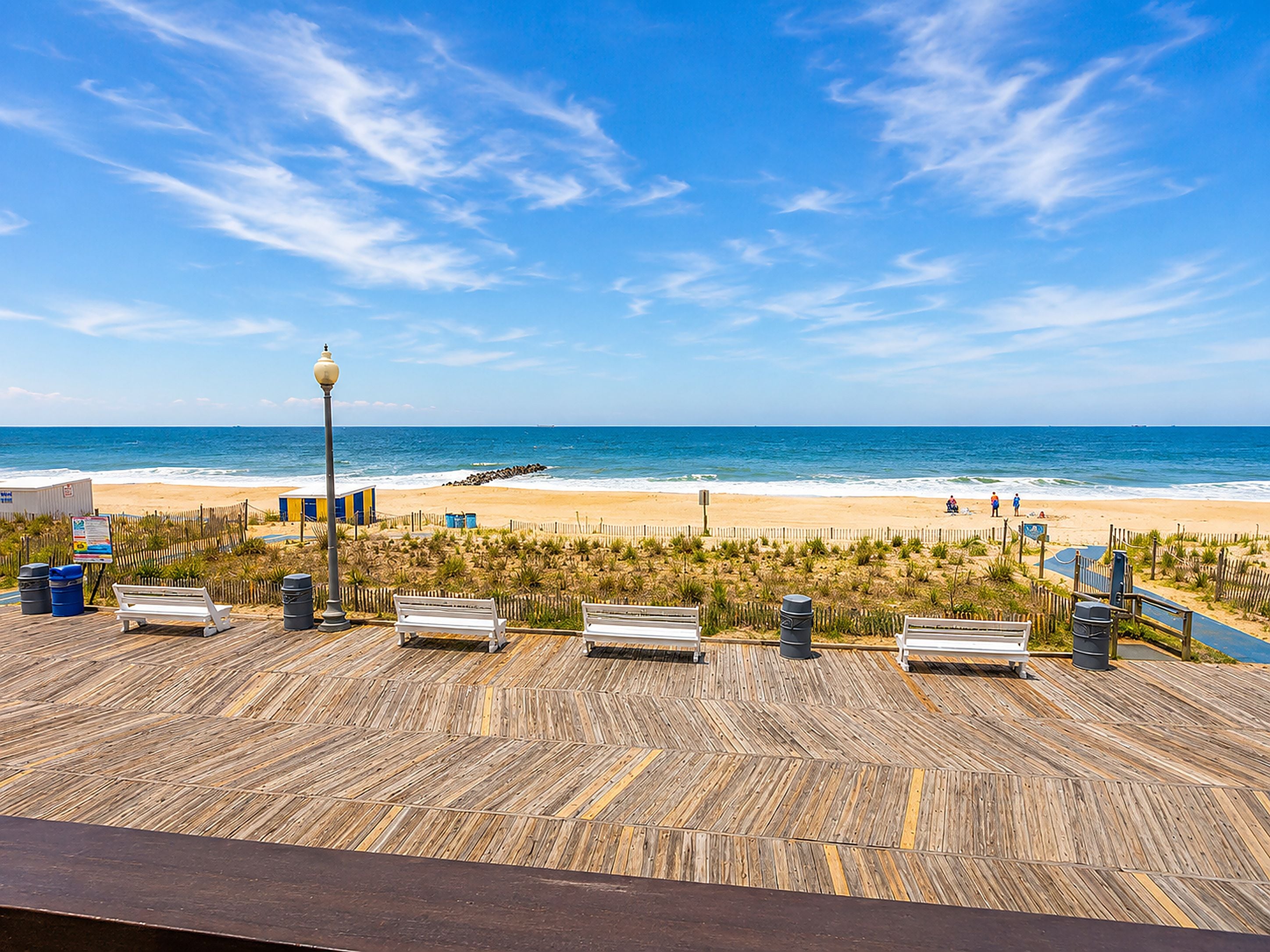 A wooden deck with benches overlooking a beach.