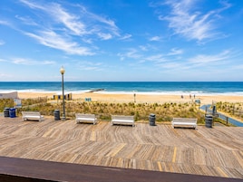 A wooden deck with benches overlooking a beach.