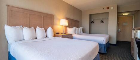 Een hotelkamer met twee bedden, een bureau, een lamp en een kapstok.