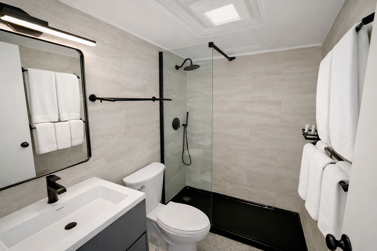 Un baño moderno con cabina de ducha de cristal, un lavamanos blanco y un inodoro.