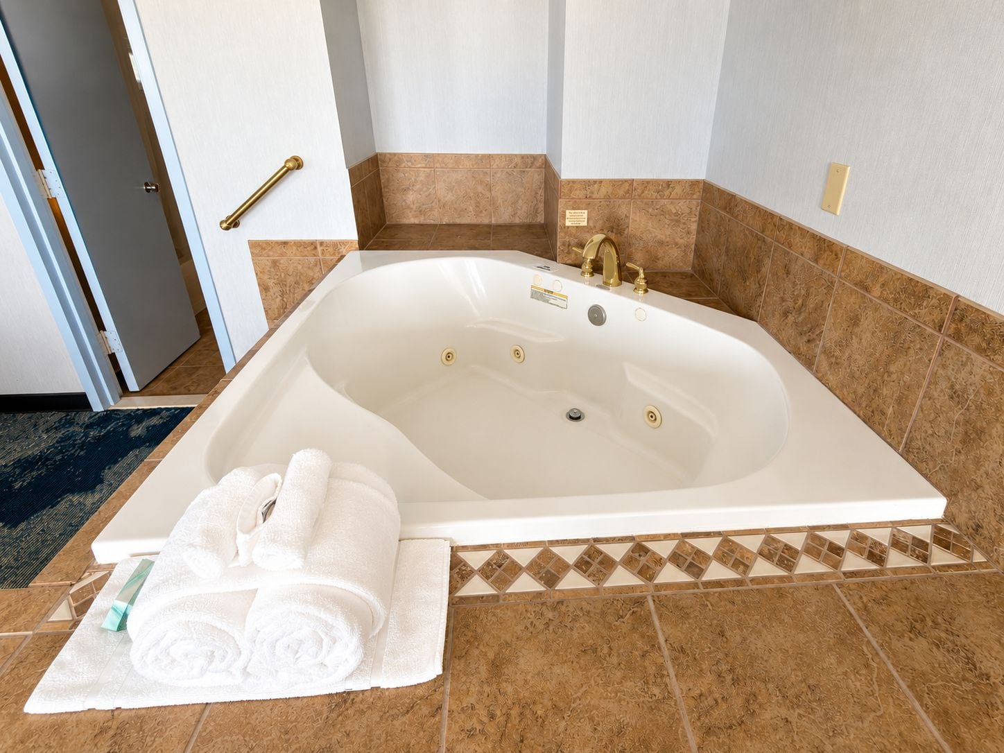 Eine große Badewanne mit Duschkopf, Handtuch und Fußmatte.