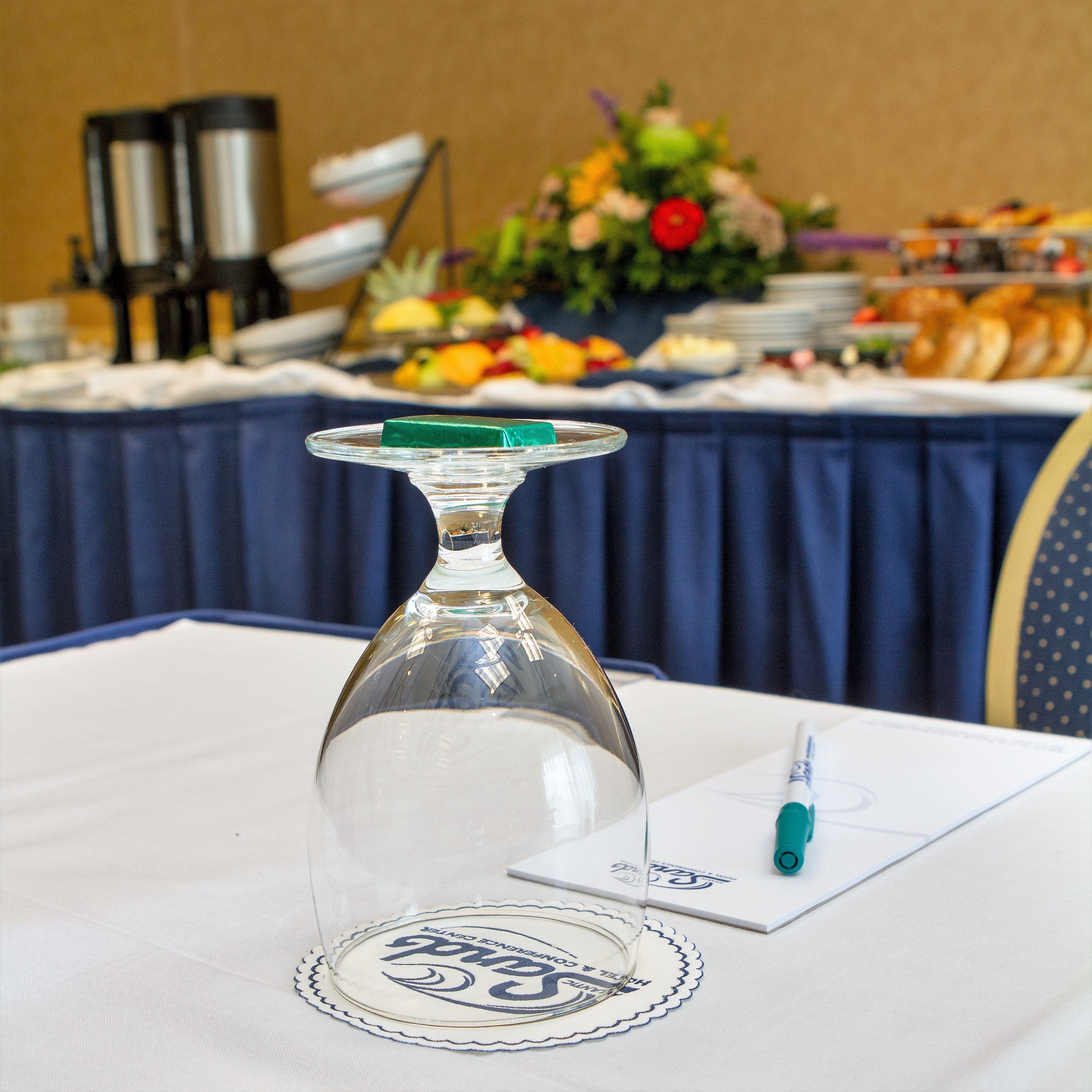 A clear glass vase on a table with a placemat, a pen, and a notepad.