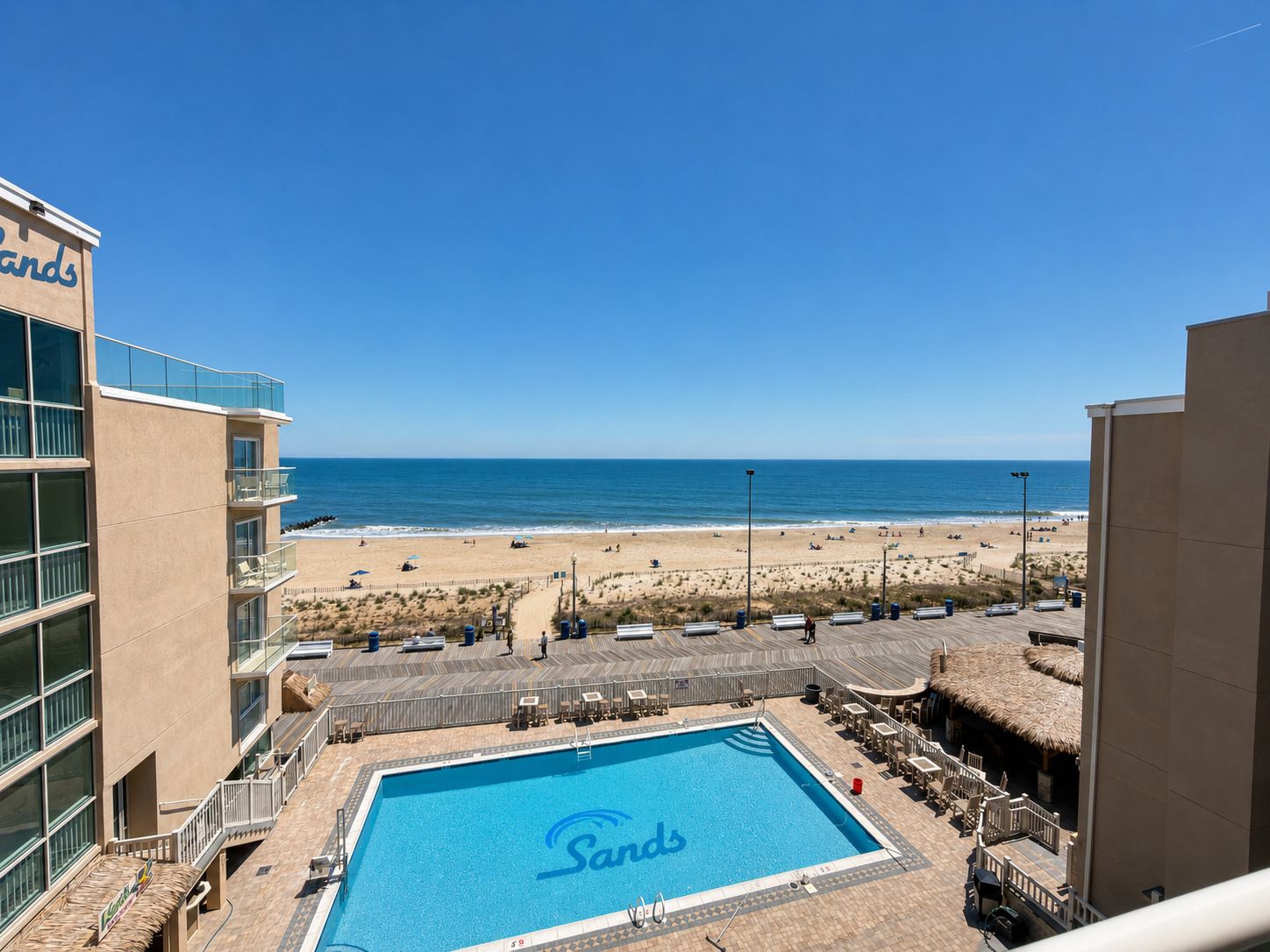 A hotel with a pool, beach view, and a sign reading 'Sands'.