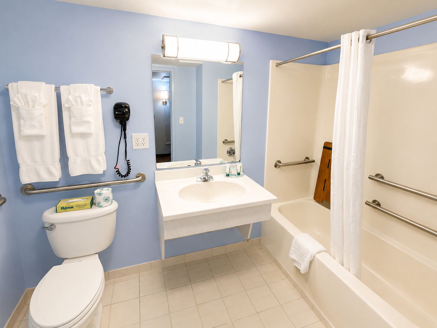 A bathroom with a toilet, sink, mirror, and shower.