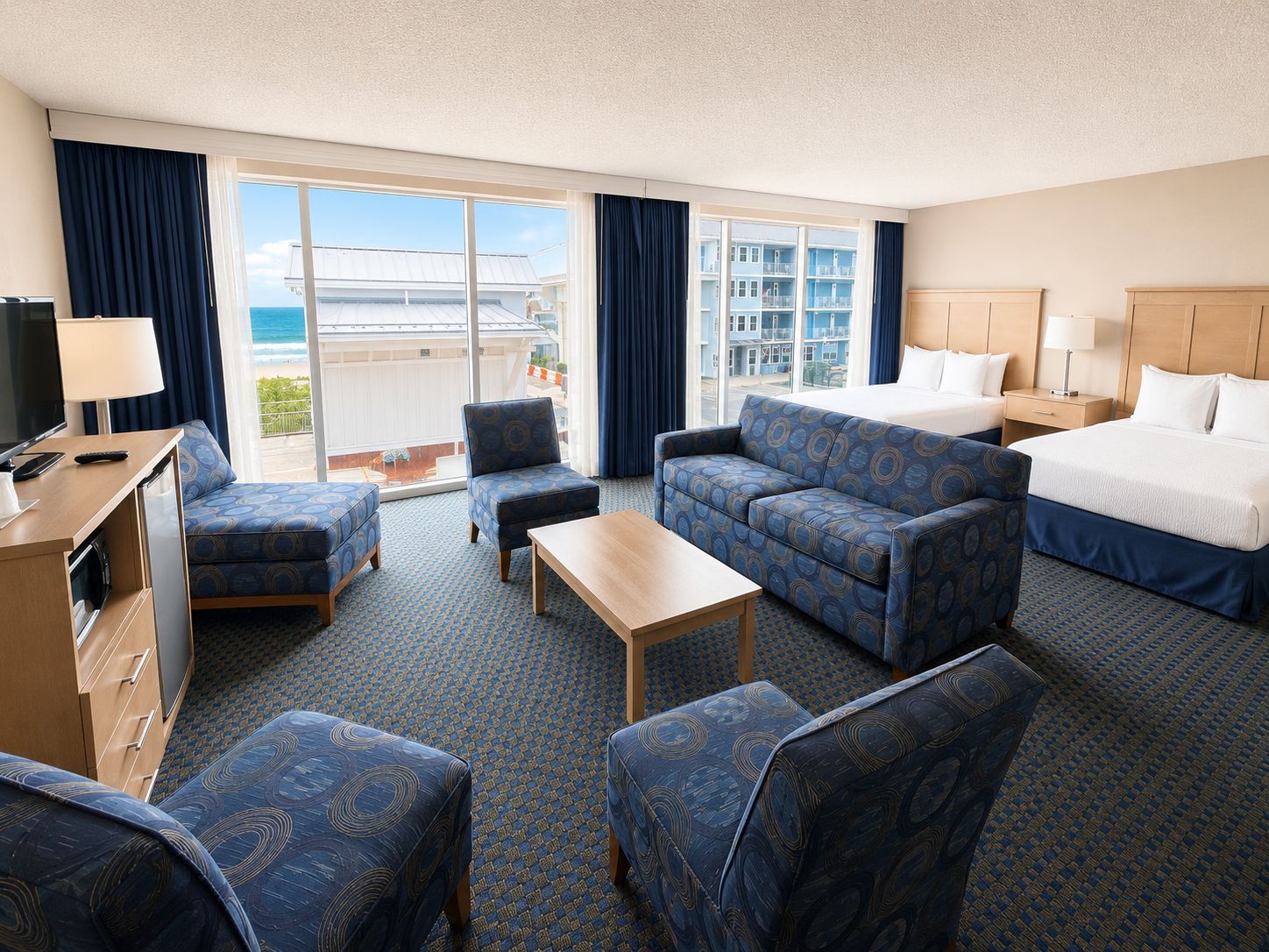 A hotel room with a bed, two sofas, a coffee table, a TV, and a desk.