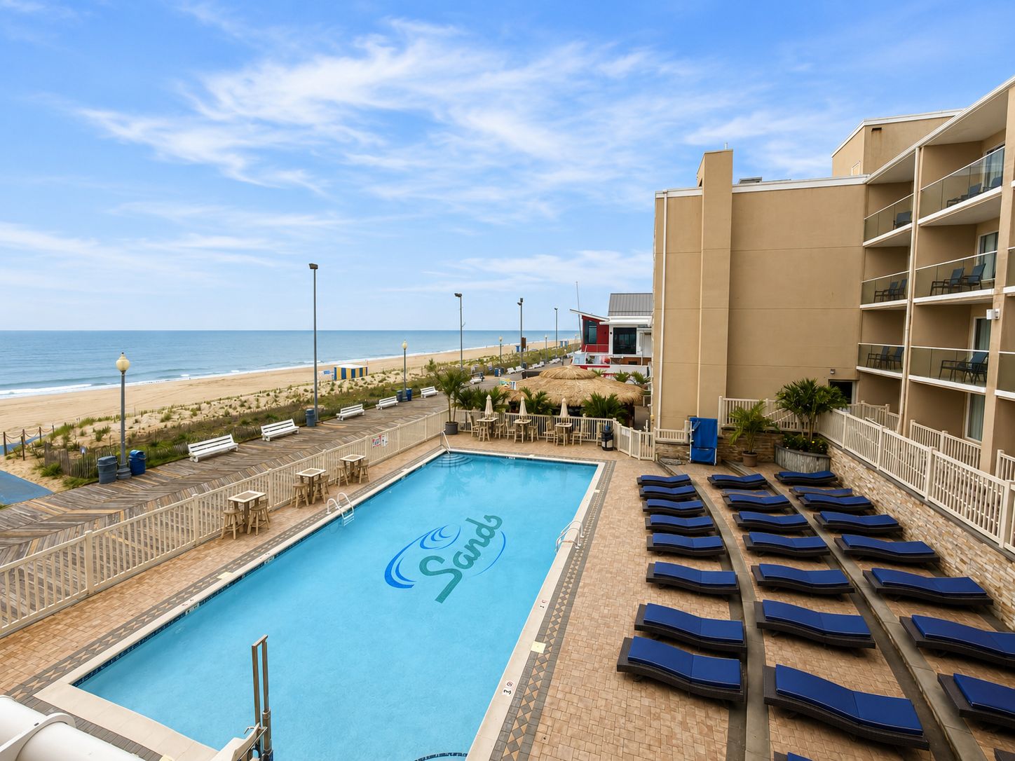 A swimming pool with lounge chairs and a view of the beach.
