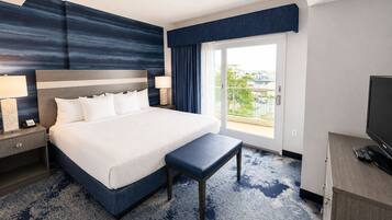 Une chambre d’hôtel avec un grand lit, un banc, une télévision et une vue sur l’extérieur.