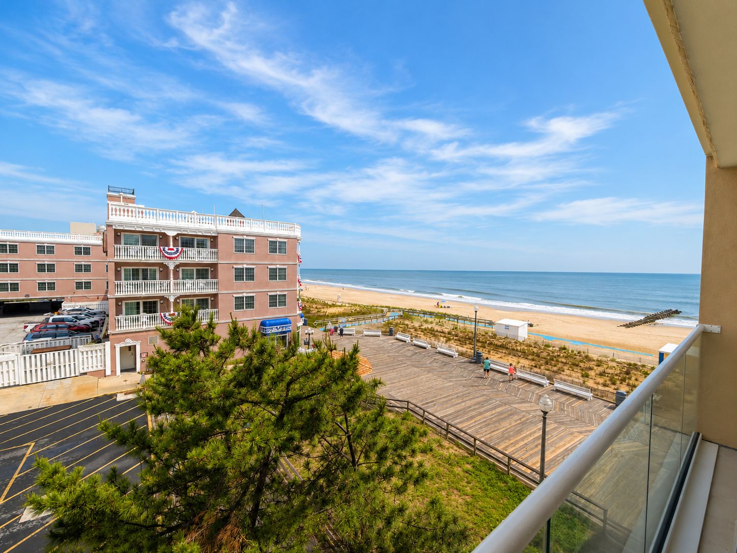 A beachfront hotel with a parking lot, a boardwalk, and a view of the ocean.