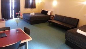 A hotel room with a bed, a sofa, a desk, and a chair. - New Castle Motor Lodge (Rotorua)